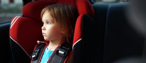 Child in auto baby seat in car looking at window